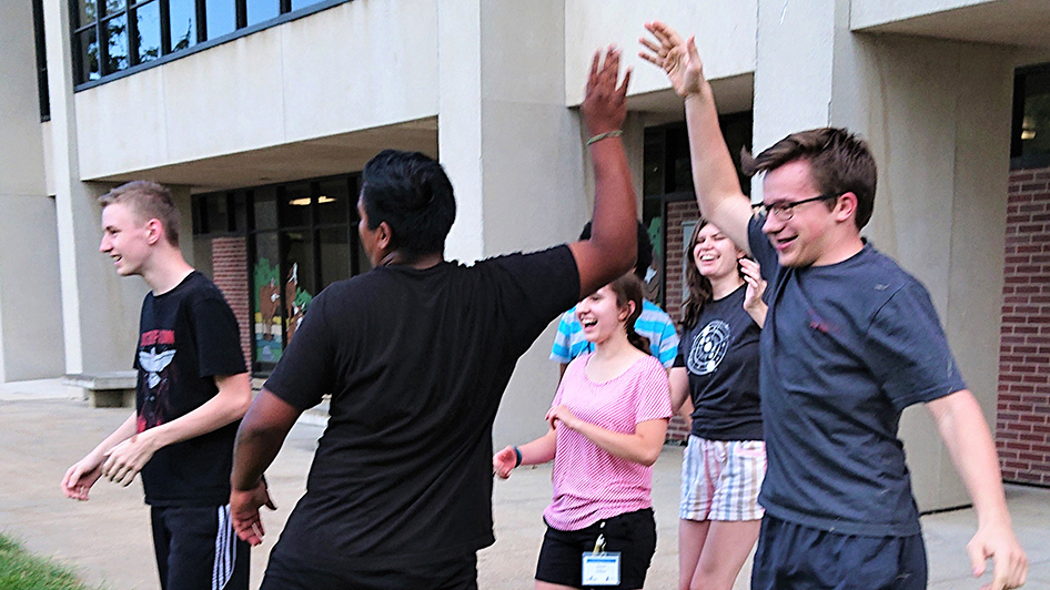 Young Nebraska Scientists celebrate an achievement with a group high-five during a Summer 2021 camp at Nebraska Wesleyan University.