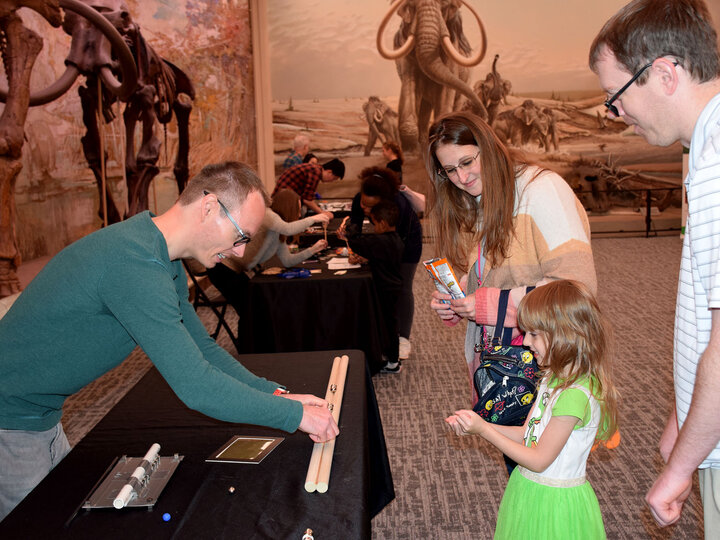 Robert Streubel showing his magnet experiment to a family.