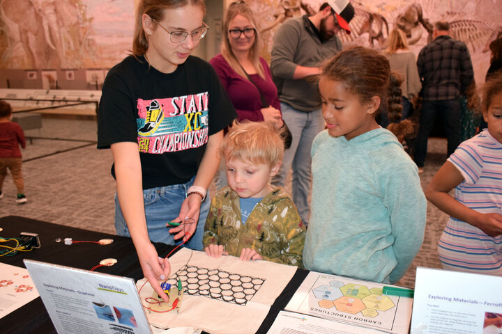 A group of kids are engaged in a graphene demonstration.
