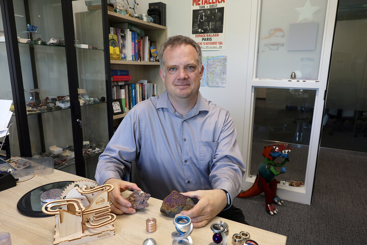 Jeremy Armstrong sitting in his office surrounded by geodes and physics-related toys.